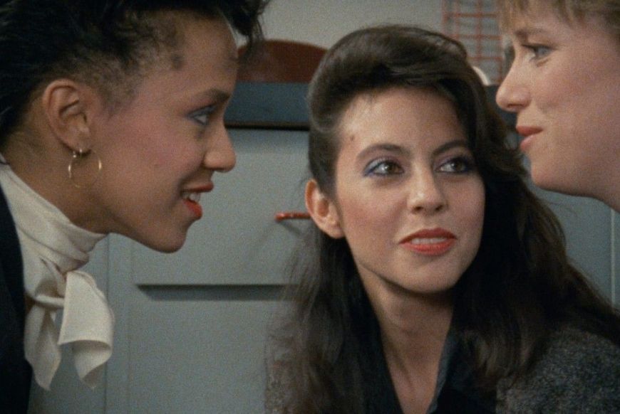 three 70s women in an office looking at one another